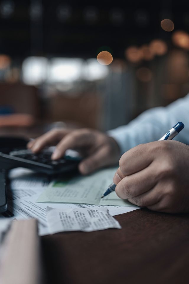 Mani con una penna e una calcolatrice su estratti stampati