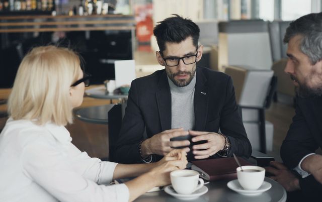 Tre persone al tavolo che osservano dei dati su un telefono