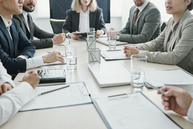 Una riunione in corso attorno a un tavolo con documenti e portatili