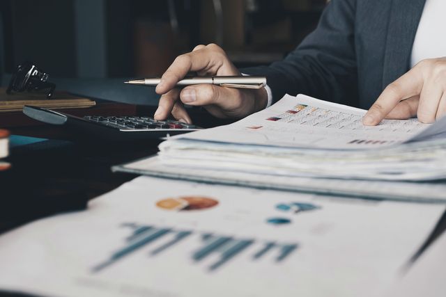 Mani con una penna su report stampati con tabelle e grafici
